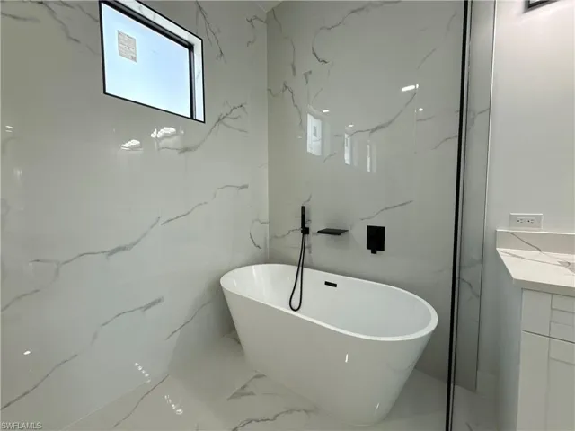Bathroom featuring vanity, a soaking tub, and stone wall