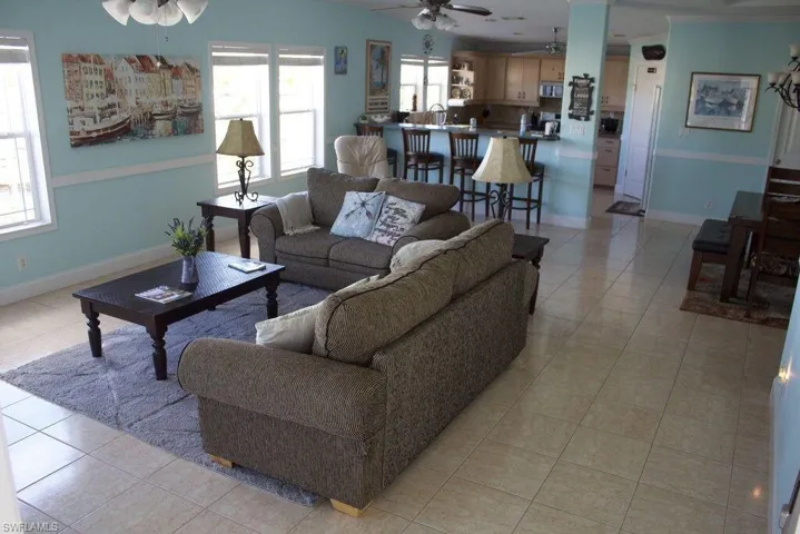 Living room with ceiling fan and light tile patterned flooring