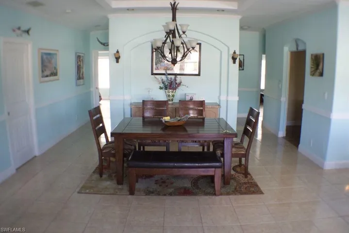 Dining area featuring a chandelier, light tile patterned floors, and crown molding