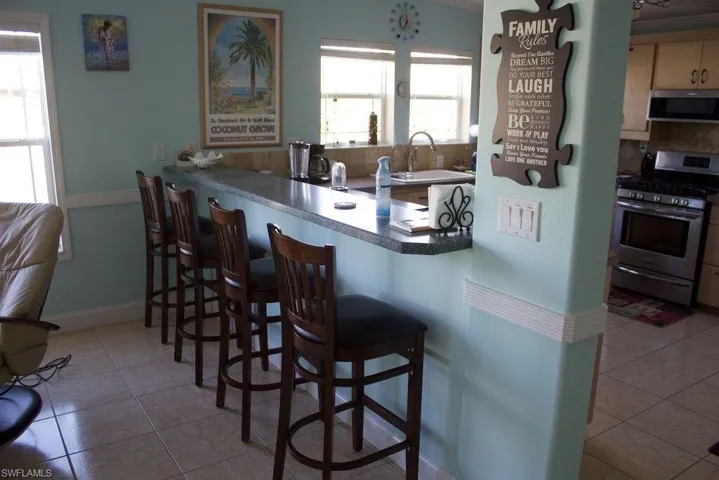 Kitchen featuring appliances with stainless steel finishes, light tile patterned floors, backsplash, and a breakfast bar