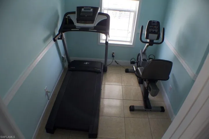 Exercise room with tile patterned floors and baseboards