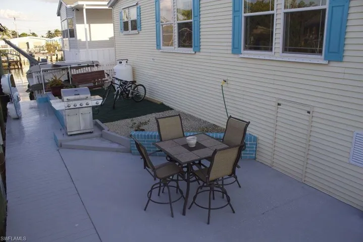 View of patio featuring grilling area, outdoor dining space, and a hot tub