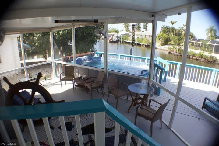 Sunroom with a water view and a hot tub