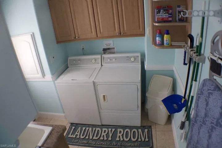 Laundry room featuring cabinet space, washer and clothes dryer, and light tile patterned floors