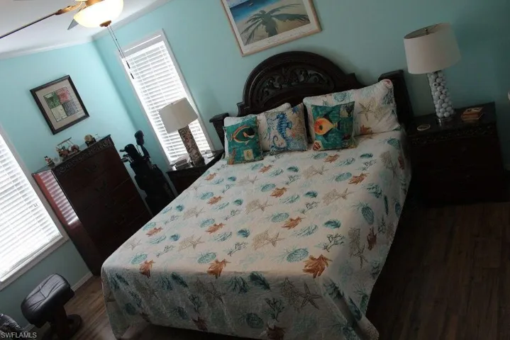 Bedroom with wood finished floors, multiple windows, and ornamental molding