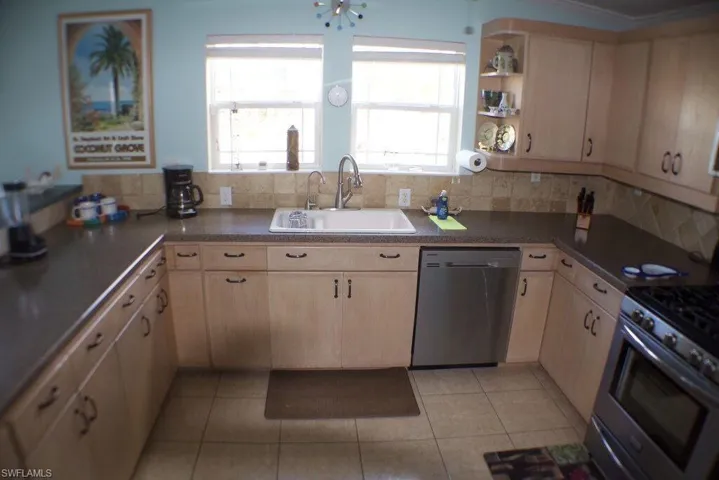 Kitchen with stainless steel appliances, light brown cabinets, light tile patterned floors, tasteful backsplash, and open shelves