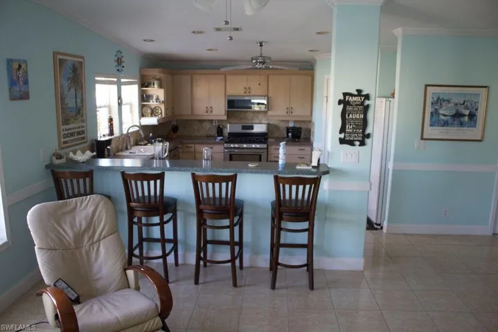 Kitchen with appliances with stainless steel finishes, crown molding, a ceiling fan, backsplash, and a peninsula