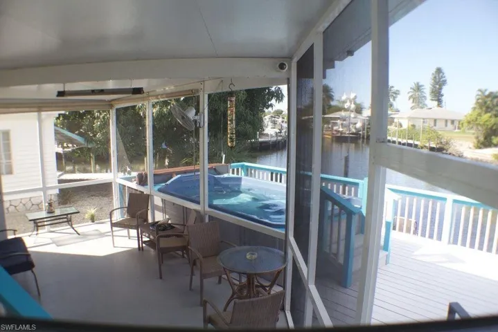 Sunroom / solarium with a water view and a hot tub