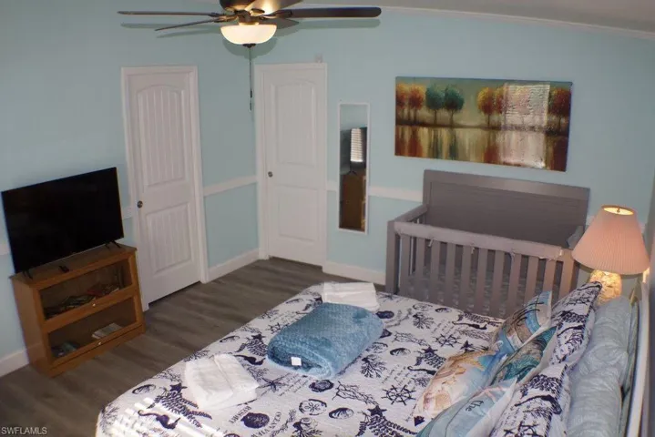 Bedroom featuring wood finished floors, ornamental molding, and a ceiling fan
