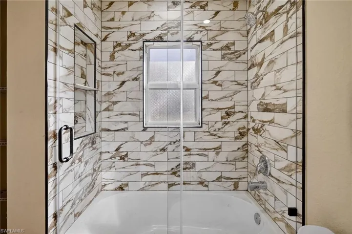 Bathroom with bath / shower combo with glass door