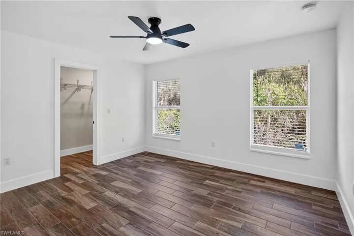 Unfurnished bedroom featuring wood tiled floors, ceiling fan, and a walk in closet