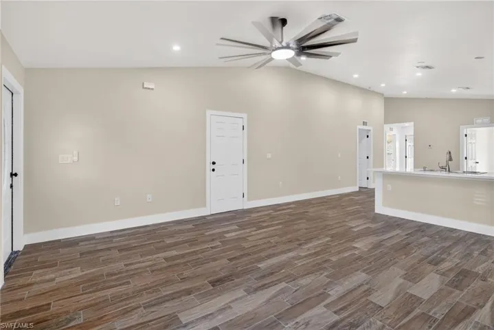 Unfurnished living room featuring lofted ceiling, recessed lighting, wood finish floors, and ceiling fan