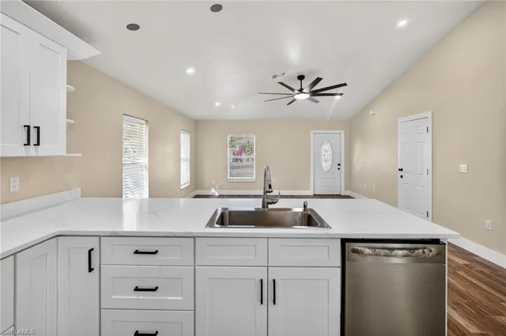 Kitchen featuring open shelves, dishwasher, white cabinets, a peninsula, and open floor plan