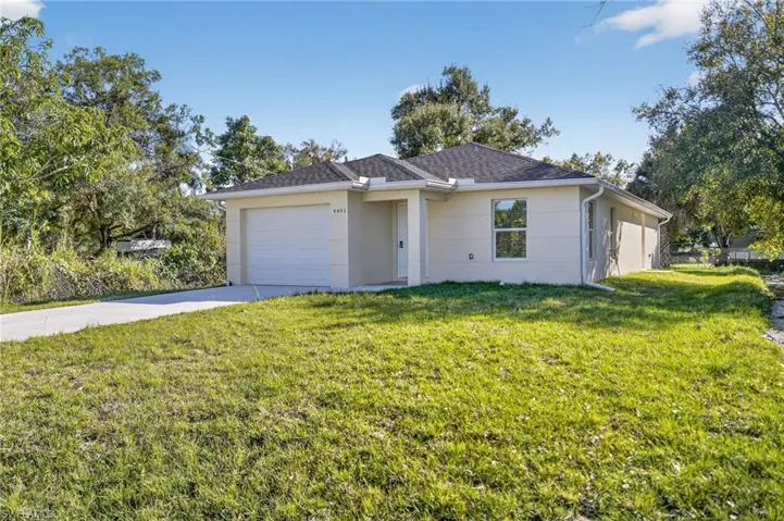 Single story home featuring a front yard, stucco siding, driveway, and a garage