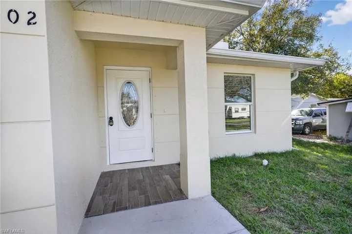 Property entrance with a lawn and stucco siding