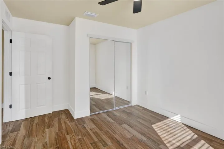 Unfurnished bedroom featuring wood finished floors, a closet, and ceiling fan
