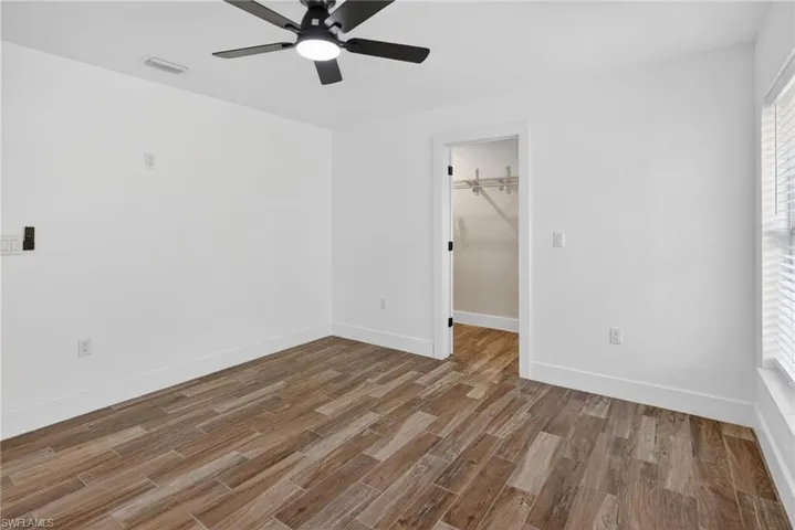 Unfurnished bedroom with wood tiled floors, a ceiling fan, and a walk in closet