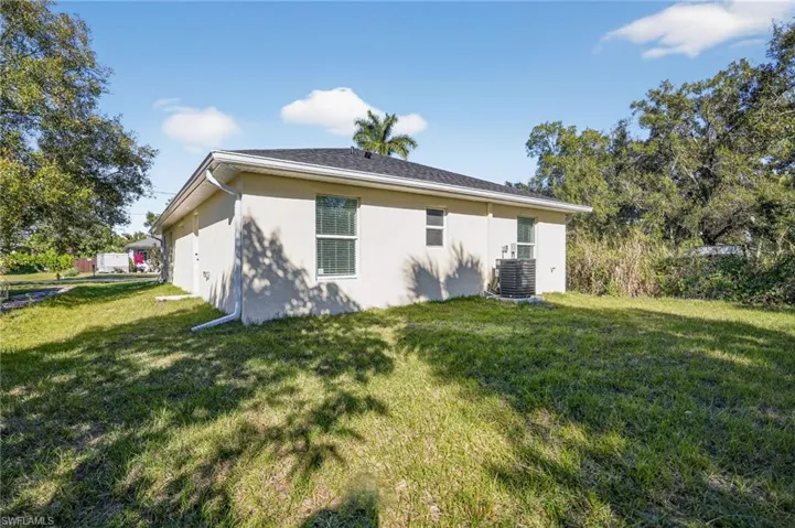 Back of house featuring a lawn and stucco siding