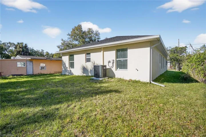 Back of house featuring a lawn and stucco siding