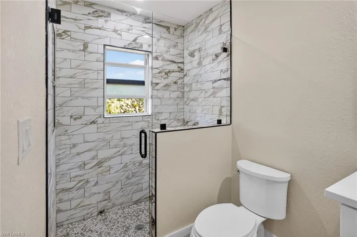 Full bathroom with a textured wall, a stall shower, and vanity