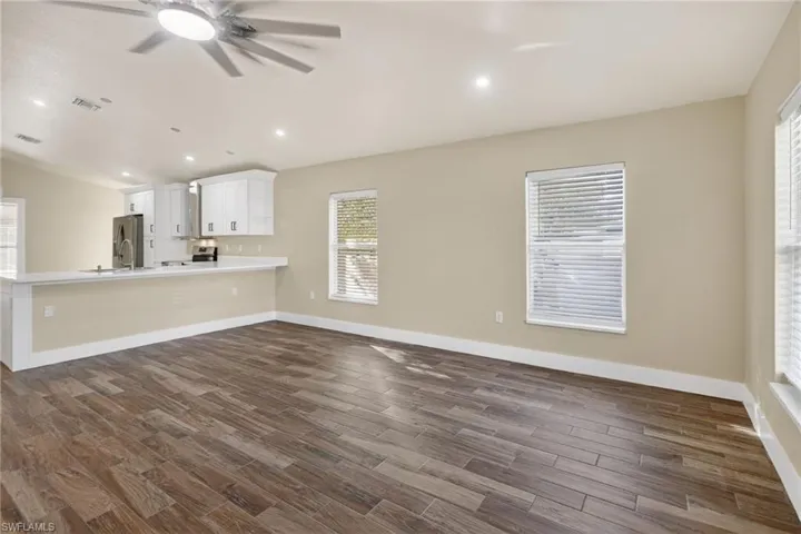 Unfurnished living room featuring wood finish floors, lofted ceiling, ceiling fan, and recessed lighting