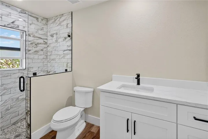 Bathroom featuring vanity, a stall shower, dark wood-style floors, and a textured wall