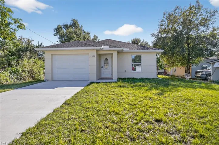Single story home featuring driveway, a front lawn, an attached garage, and stucco siding
