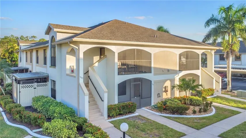 View of front of house with stucco siding, a shingled roof, stairway, and a balcony