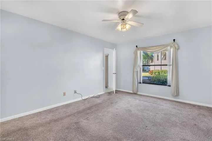 Carpeted empty room featuring baseboards and ceiling fan