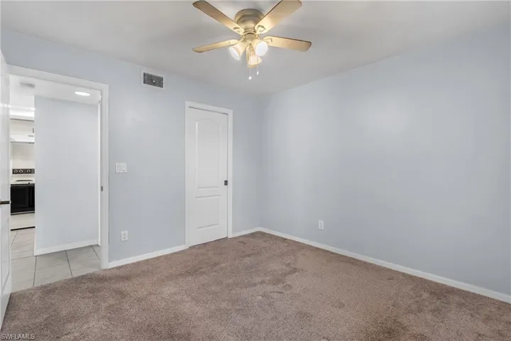 Unfurnished bedroom with light carpet, ceiling fan, and a closet