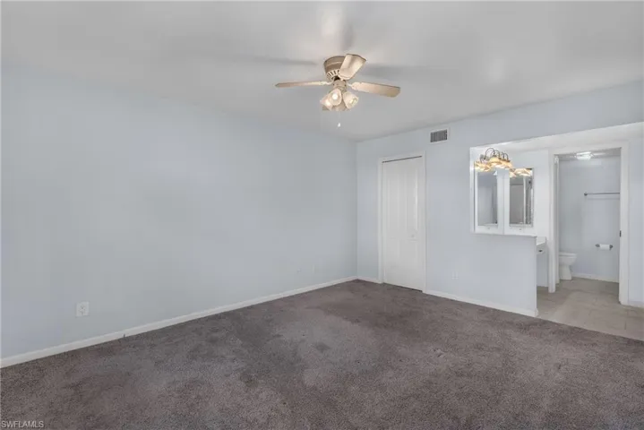 Carpeted primary bedroom with ceiling fan and baseboards