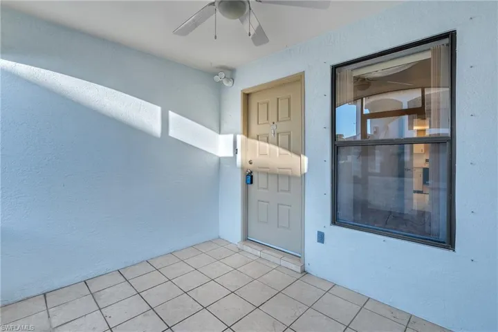 Entrance to property with stucco siding and ceiling fan