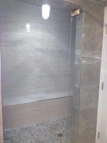 Bathroom featuring tile walls, a stall shower, and wood finished floors