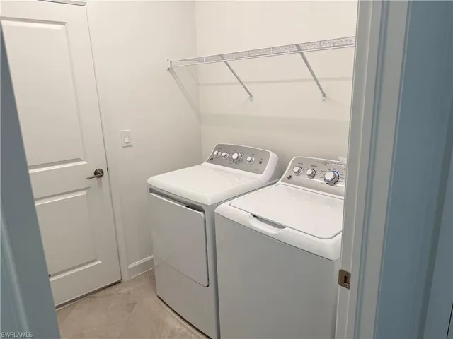 In-residence laundry area featuring tile flooring, a solid-core door, and built-in wire shelving
