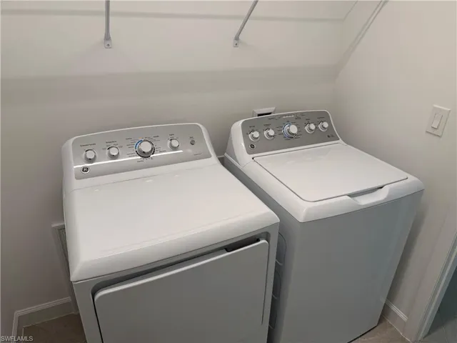 Laundry area featuring side-by-side white top-load washer and dryer units and wall-mounted wire shelving