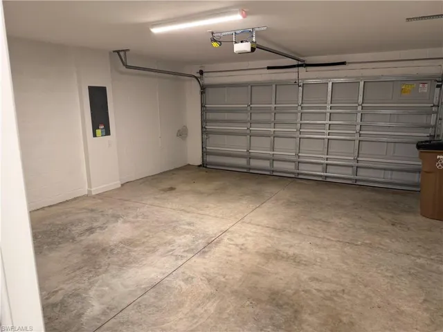 Two-car garage featuring a concrete floor, sectional overhead door, automated door opener, and interior lighting