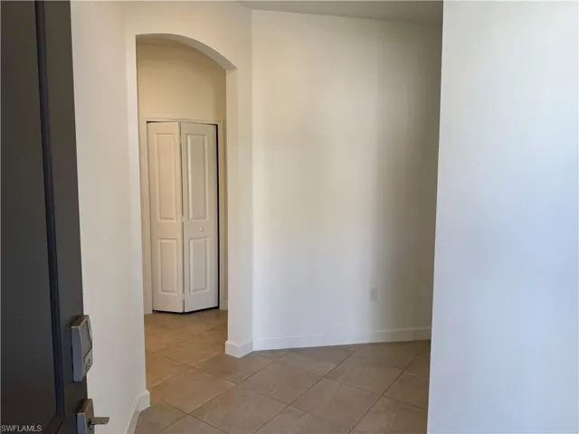 Neutral-toned tile flooring, arched architectural opening, and bi-fold closet doors