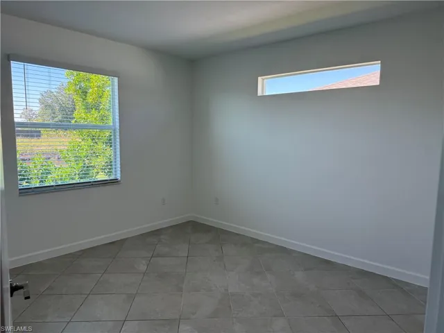 Neutral-toned tile flooring, large single-hung window, and high-set horizontal transom window
