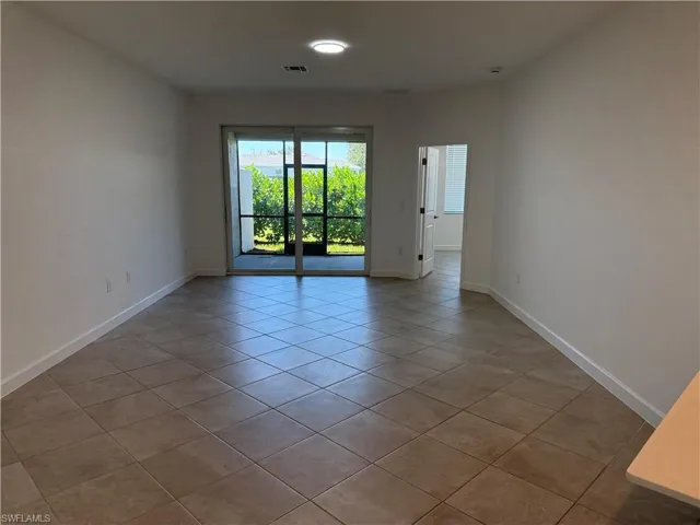Neutral-toned tile flooring, recessed ceiling lighting, and sliding glass doors leading to a screened-in patio