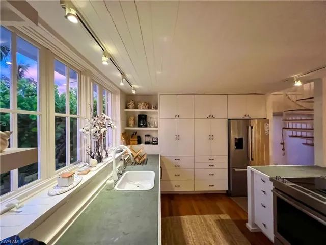 Kitchen featuring white cabinets, dark wood-type flooring, track lighting, appliances with stainless steel finishes, and sink