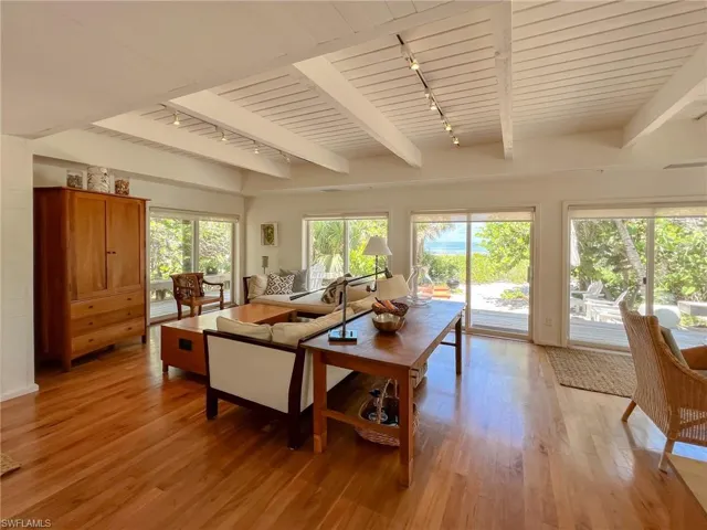 Living room featuring rail lighting, light wood-type flooring, and beam ceiling