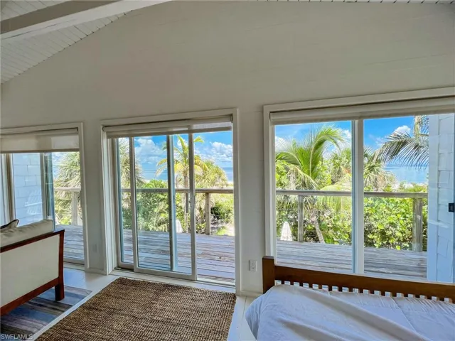 Unfurnished bedroom with hardwood / wood-style floors, access to outside, and vaulted ceiling with beams