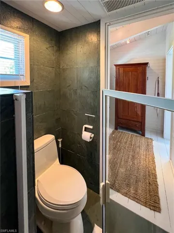 Bathroom featuring tile patterned flooring, toilet, and tile walls