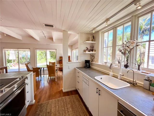 Kitchen with light hardwood / wood-style flooring, rail lighting, electric range oven, wooden ceiling, and sink