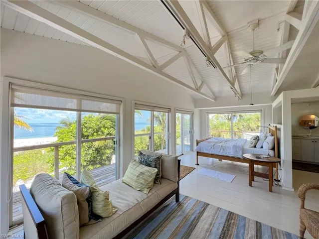 Sunroom / solarium with vaulted ceiling with beams, wood ceiling, rail lighting, and ceiling fan