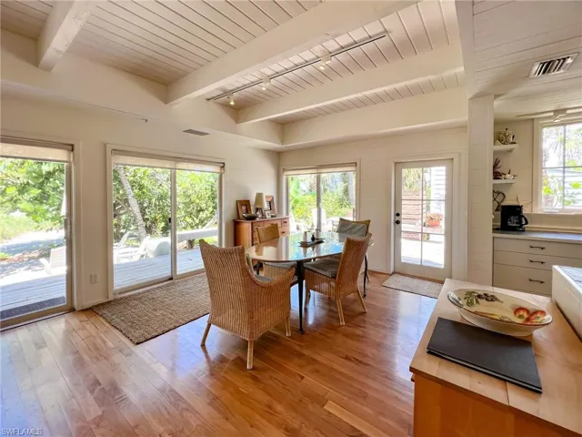 Dining area featuring beamed ceiling, light wood-type flooring, a healthy amount of sunlight, and wooden ceiling