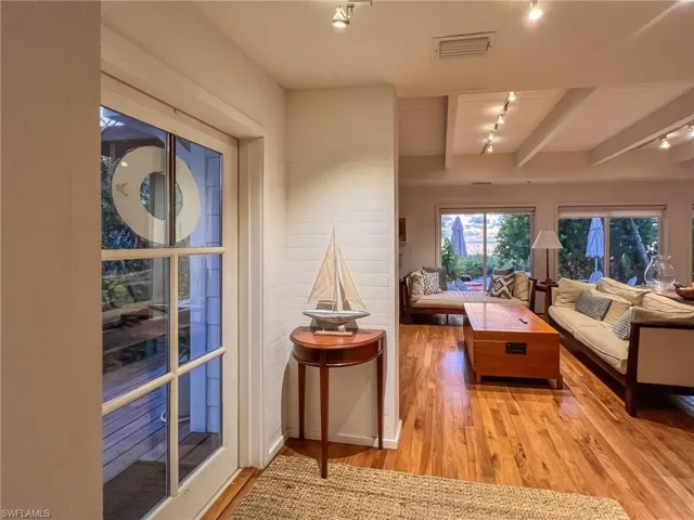 Living room with beamed ceiling, light hardwood / wood-style flooring, and rail lighting