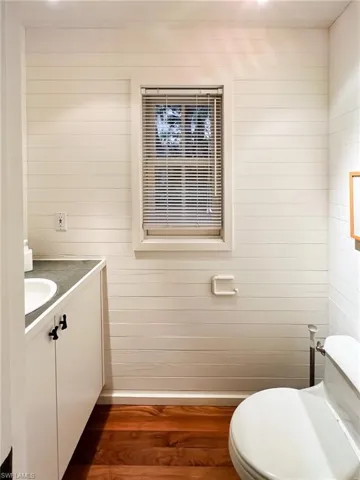 Bathroom featuring hardwood / wood-style floors, wooden walls, toilet, and vanity