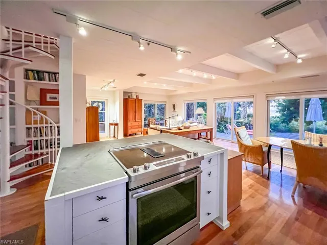 Kitchen with beamed ceiling, light hardwood / wood-style flooring, track lighting, stainless steel electric range oven, and white cabinetry