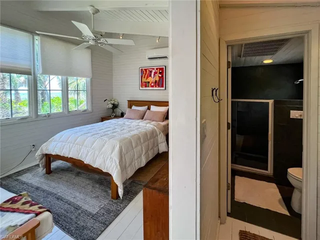 Bedroom featuring a wall mounted AC, vaulted ceiling, and ceiling fan